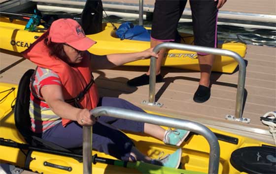 A kayak instructor teaches a kayaker how to use the accessible launch